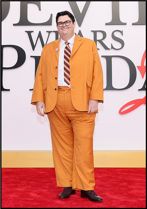 Caleb Hearon wears a bright orange suit paired with a striped tie.