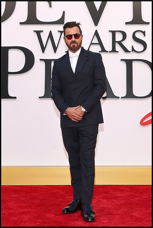 Justin Theroux wears a black suit with a white shirt, tie, and sunglasses.
