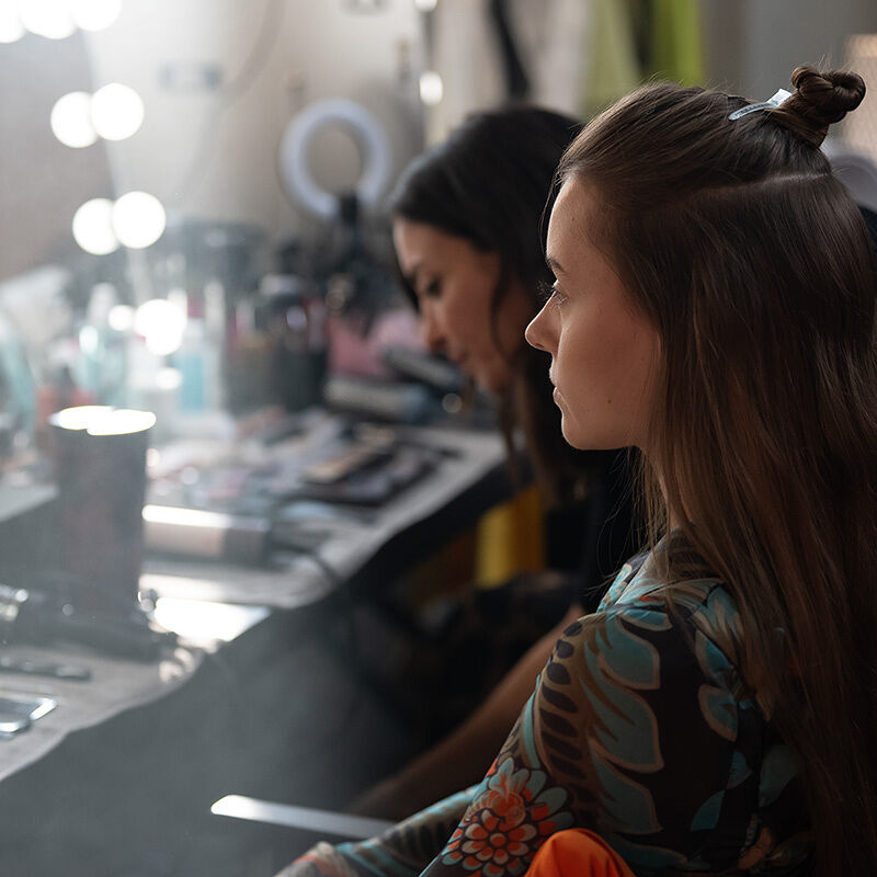 A model sits patiently in the hair and makeup chair as the stylist looks for just the right tool to complete the partial updo for the Runway show at Milan Fashion Week.
