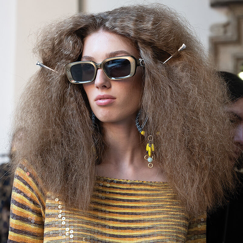 A big-haired model in gold sunglasses and giant earrings seems unfazed by the pre-catwalk chaos that occurs backstage before the big Runway magazine show at Milan Fashion Week begins.