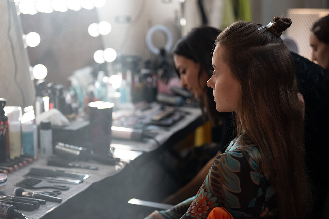 A model sits patiently in the hair and makeup chair as the stylist looks for just the right tool to complete the partial updo for the Runway show at Milan Fashion Week.