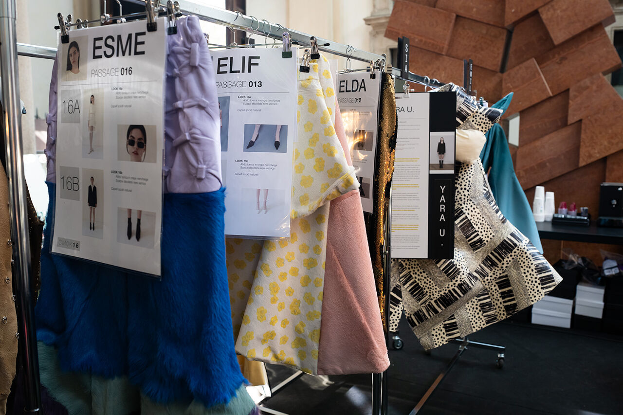 Milan Fashion Week Runway show complete looks hang on the rack before the catwalk chaos begins, each with thorough instructions detailing which model is supposed to wear it, how she is supposed to wear it and with what accessories and hairstyle.