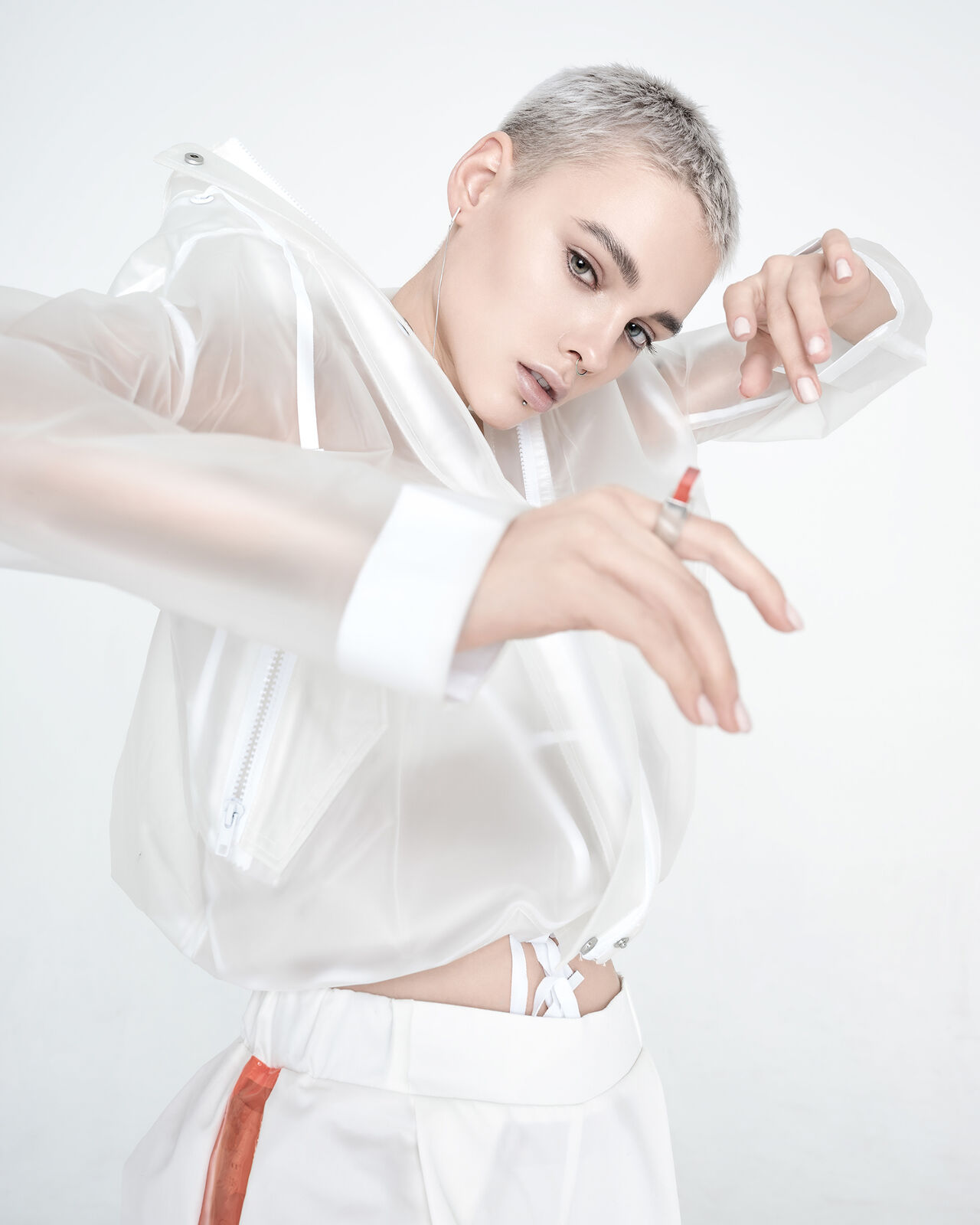 A model’s see-through raincoat puts the fun in functional. Her stark mostly white look is a designer spin on comfortable streetwear.