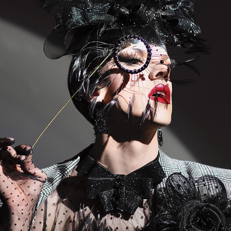 Drag performer Utica Queen (née Ethan Mundt) strikes a rebellious pose in a high-glam black corseted dress, tall jeweled headpiece made in collaboration with Edward Smith and shimmery statement gloves.