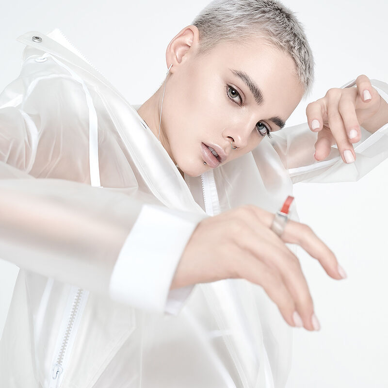 A model’s see-through raincoat puts the fun in functional. Her stark mostly white look is a designer spin on comfortable streetwear.