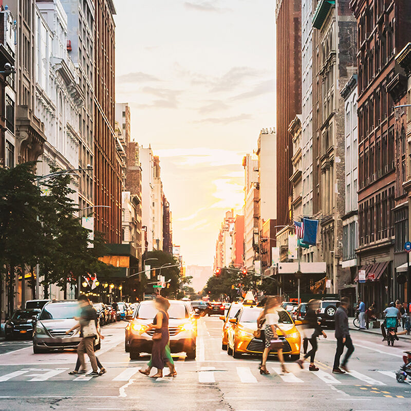 Taxis wait for fashionable New Yorkers to cross a bustling Manhattan street in the late afternoon.