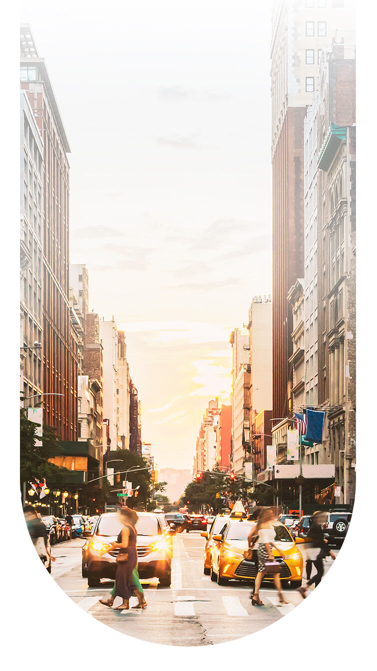 Taxis wait for fashionable New Yorkers to cross a bustling Manhattan street in the late afternoon.